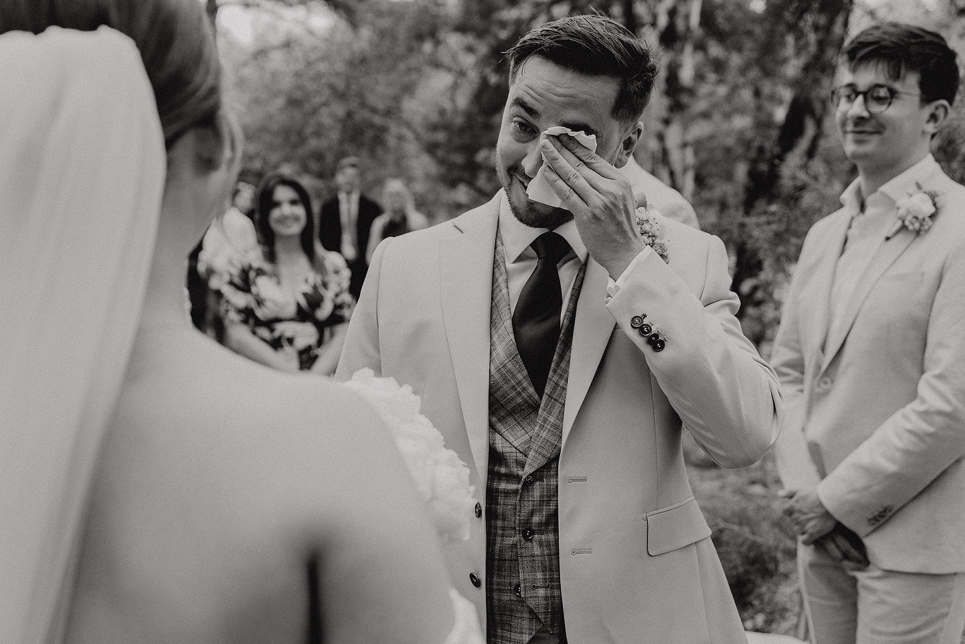 Pan Młody ocierający łzy wzruszenia podczas ceremonii zaślubin w Sielsko Anielsko, z Panną Młodą widoczną z tyłu, uchwycony przez Camera Folks – Wedding Photo & Video.