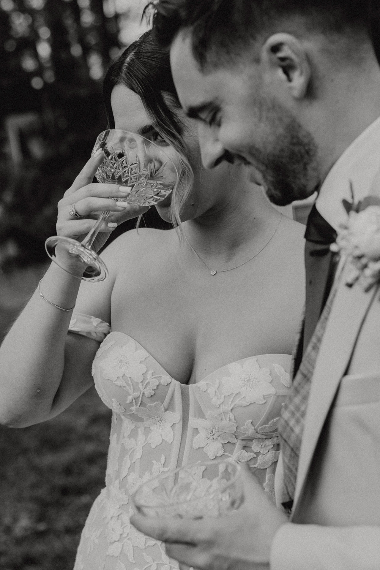 Czarno-białe zdjęcie Pary Młodej pijącej szampana z kieliszków podczas "champagne tower" na weselu w Sielsko Anielsko, z uśmiechami i radosnymi minami, sfotografowane przez Camera Folks – Wedding Photo & Video.