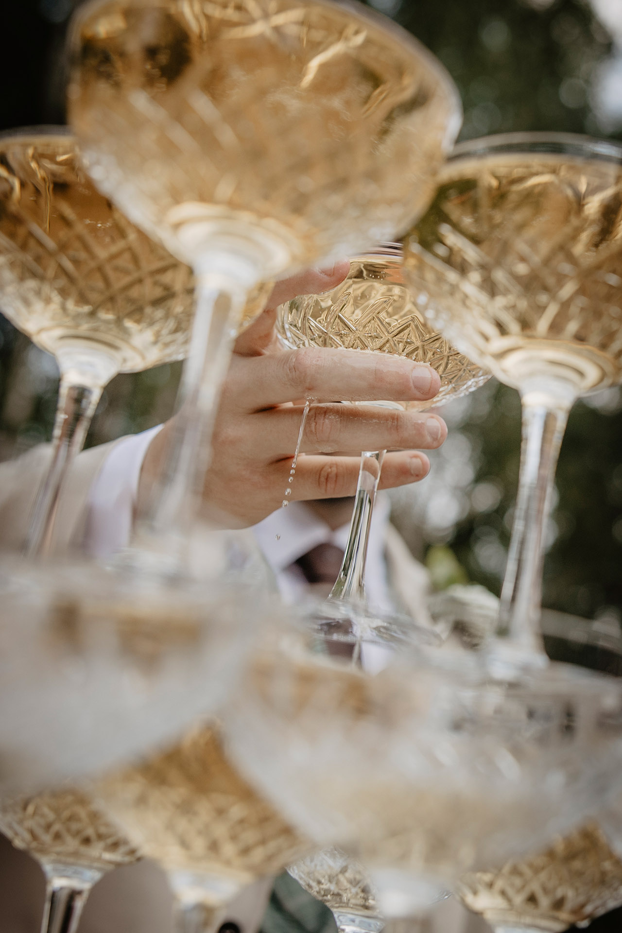 Detal: dłoń sięgająca po kieliszek szampana z piramidy, podczas "champagne tower" na weselu w Sielsko Anielsko, sfotografowany przez Camera Folks – Wedding Photo & Video.